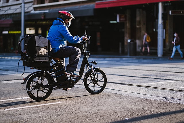Un livreur sur une moto portant un masque